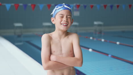 portrait of boy standing by edge of swimming pool ready for lesson