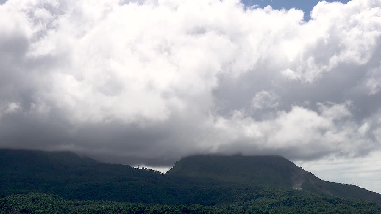 nubes blancas esponjosas e hinchadas que pasan sobre las cimas de los volcanes con una exuberante vegetación verde en una isla tropical en el lapso de tiempo de asia