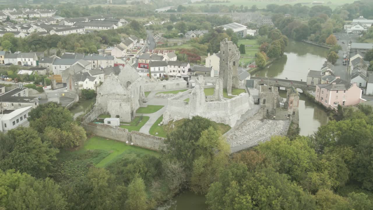 Desmond castle ruins in the town of askeaton, surrounded by houses and a river, aerial view
