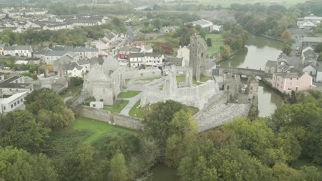 desmond castle ruins in the town of askeaton, surrounded by houses and a river, aerial view