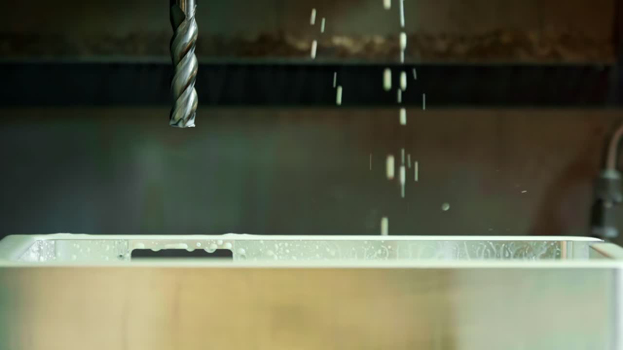 Water drips from machined metal bit in factory environment in ultra slow motion