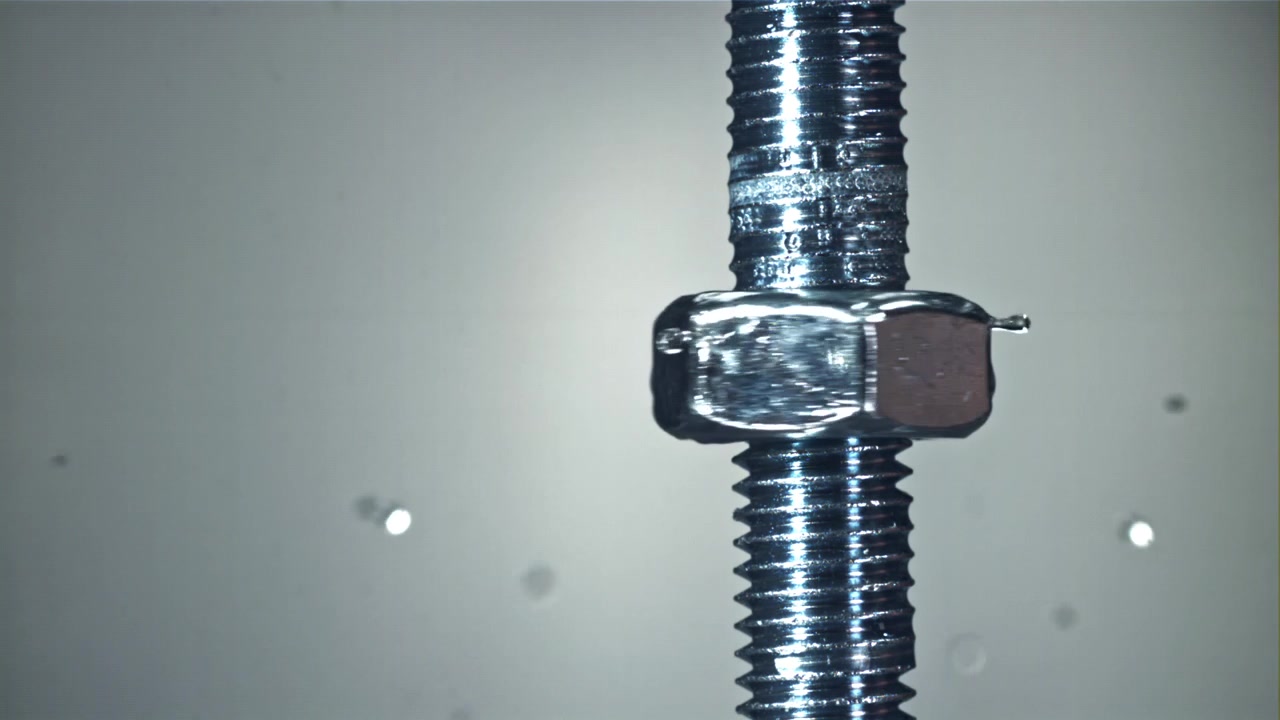 Slow Motion Water Drops Splashing on a Rotating Metal Nut and Bolt