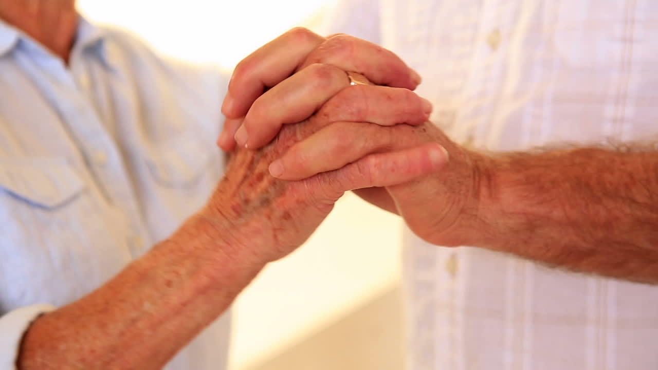 una pareja de ancianos que se unen de manos.