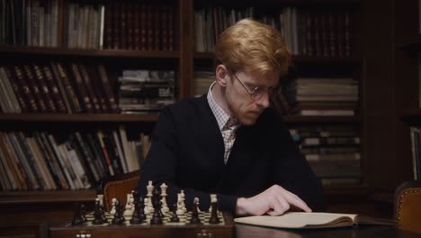 man playing chess and reading in a library