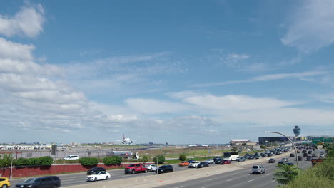 traffic on highway overlooking an active airport with an air traffic control tower