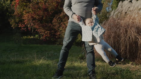 Father-plays-with-his-little-daughter-in-the-park---swings-her-from-side-to-side