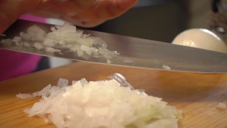 una cebolla blanca cortada en rodajas y cortada en cubitos con un cuchillo en una tabla para cortar