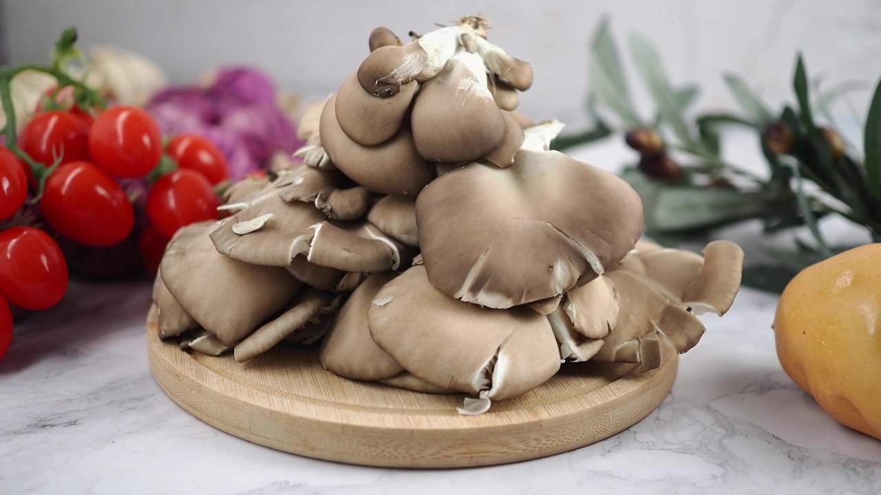 Funghi ostrica freschi su un tagliere di legno con verdure assortite