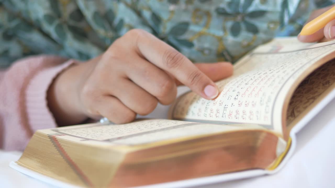 Mano di donna musulmana che legge il Corano