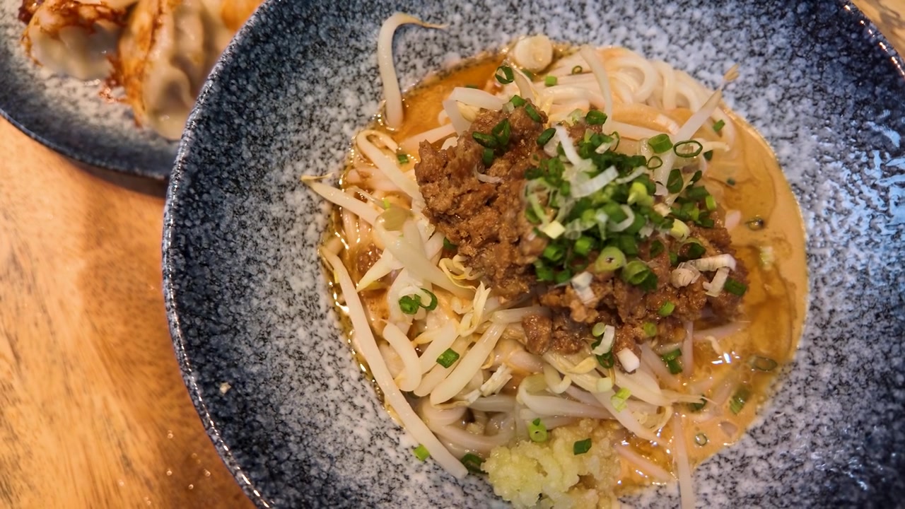 Piatto di ravioli Gyoza saltati in padella serviti con una ciotola di Ramen