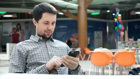 hombre usando el teléfono en una sala de comidas de un centro comercial