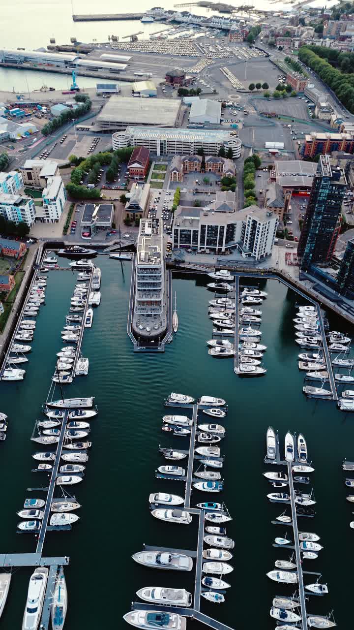 Aerial drone footage of Ocean Village marina in Southampton, showcasing boats, docks, buildings, and waterfront real estate under soft daylight at sunset shot during autumn