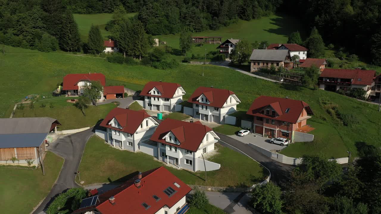 Letecký pohled dronem letícím vpřed na malou sluncem zalitou venkovskou vesnici.