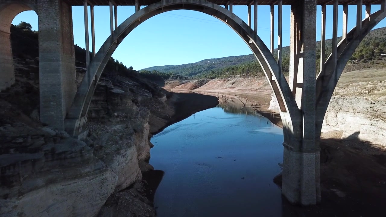 Riprese aeree del bacino di Entrepeñas vicino a Sacedón a Guadalajara, Spagna, con livelli d'acqua estremamente bassi a causa di una grave siccità. Il letto del lago prosciugato espone terreno rosso, alberi pietrificati e strutture sommerse.