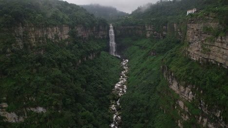 idyllic-high-waterfall-in-the-amazon-jungle-rainforest-aerial-shot,-tilt-down-shot-to-the-river-stream