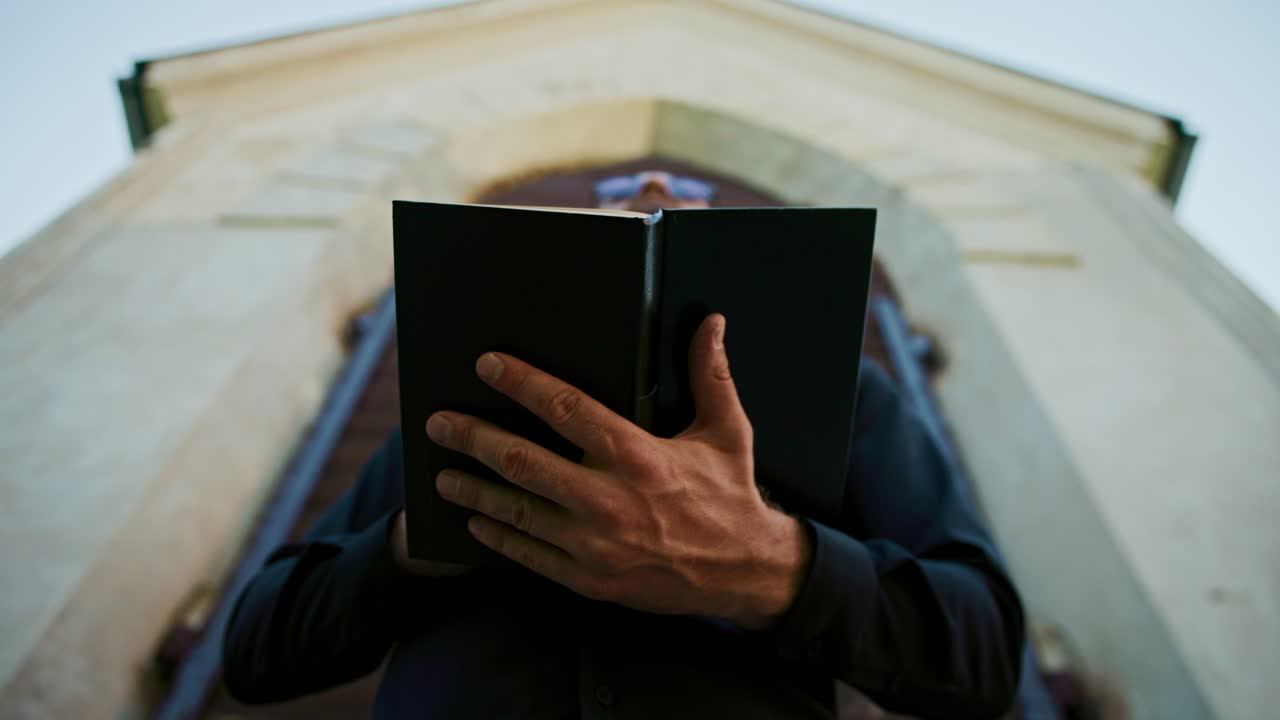 Man Reading a Book in Front of a Building