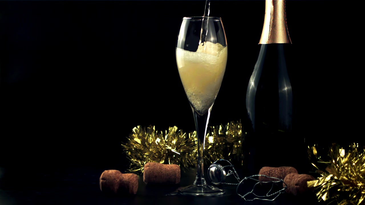 Versamento al rallentatore di champagne in un bicchiere a flûte con decorazioni festive