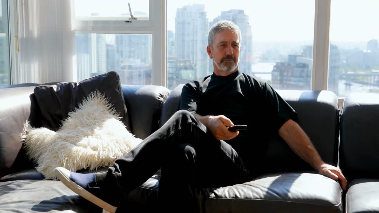 소파 4k에서 리모컨을 사용하는 사람