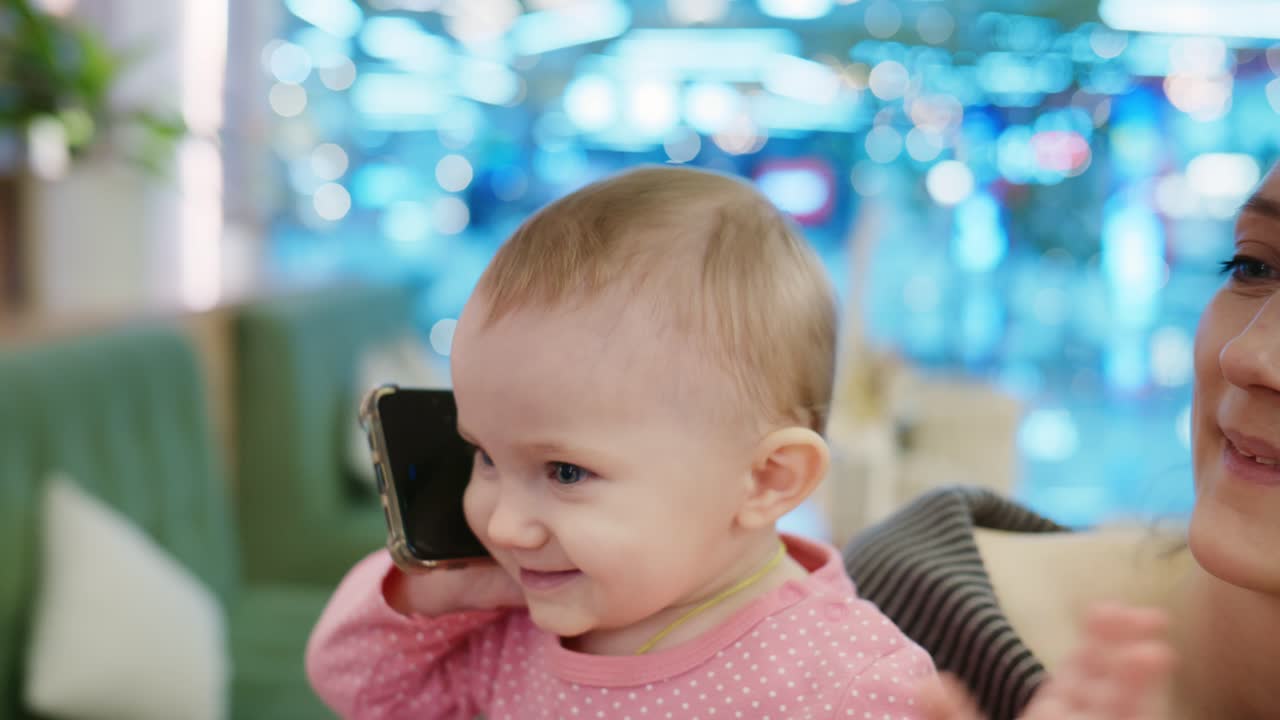 母親と一緒にスマートフォンで話す真似をするかわいい女の子の赤ちゃん。