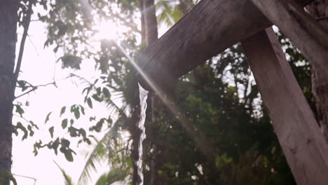 close up of water pouring out of a bamboo island shower in slow motion on the beach at punta banco, costa rica