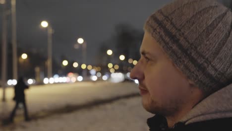 Pensive-young-man-walking-in-city-street-at-night-after-work-with-serious-expression