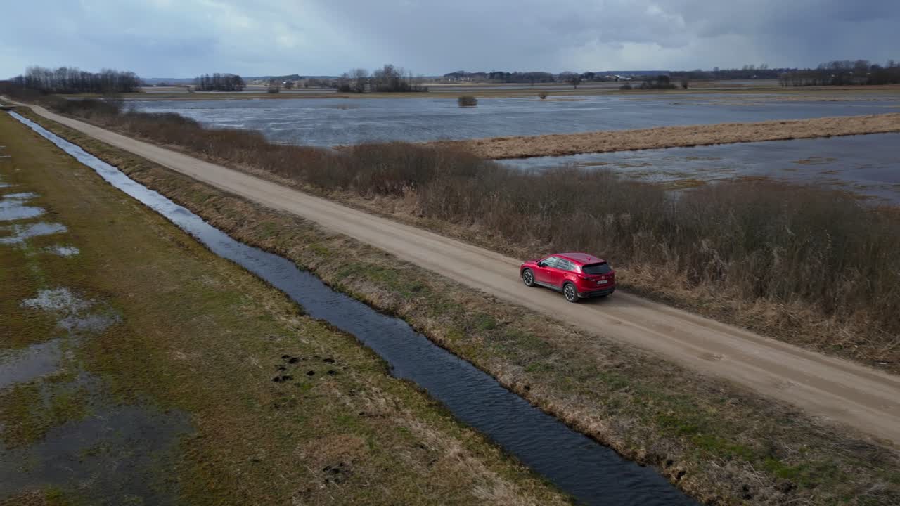 SUV Vermelho dirigindo em uma estrada de areia em um dia nublado na Polônia