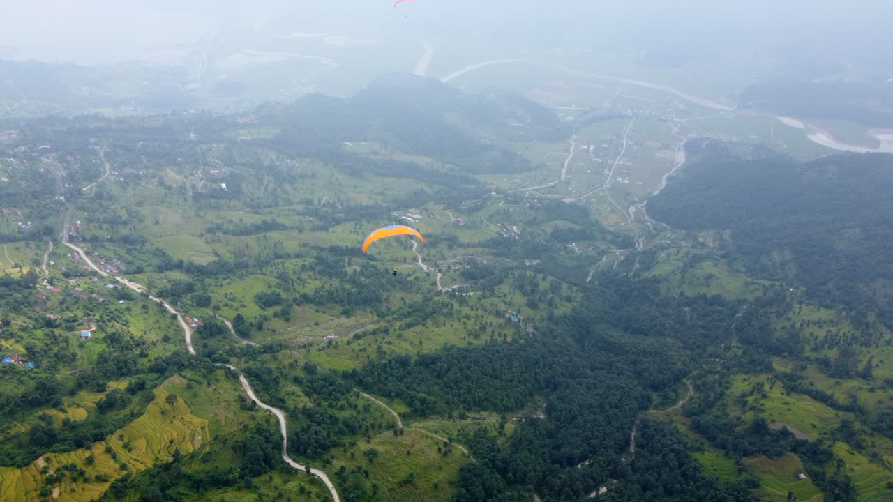 네팔 의 포카라 근처 에 있는 안개 가 가득 한 초록색 풍경 위 에 날아다니는 패러글라이더