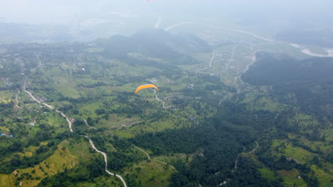 paraglider soaring above foggy green landscape near pokhara in nepal