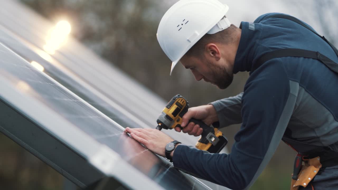 Portrait of a male solar panel installer with a cordless screwdriver