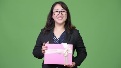 Mature beautiful Asian businesswoman holding gift box