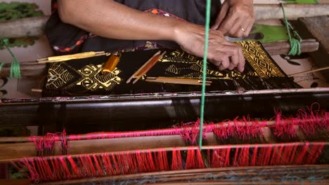 woman weaving on a loom with bobbins