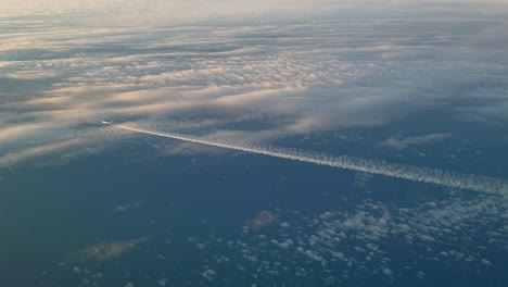 vista increíble desde la cabina de un avión que vuela alto por encima de las nubes dejando un largo rastro de aire de vapor de condensación blanco en el cielo azul