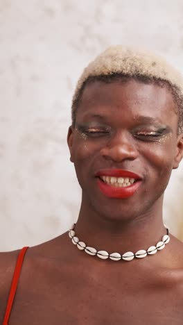 smiling person with makeup and shell necklace