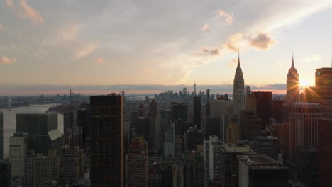 Aerial-descending-footage-of-large-city-at-dusk.-Various-tall-buildings-against-sunset-sky.-Iconic-Chrysler-and-Empire-State-buildings.-Manhattan,-New-York-City,-USA