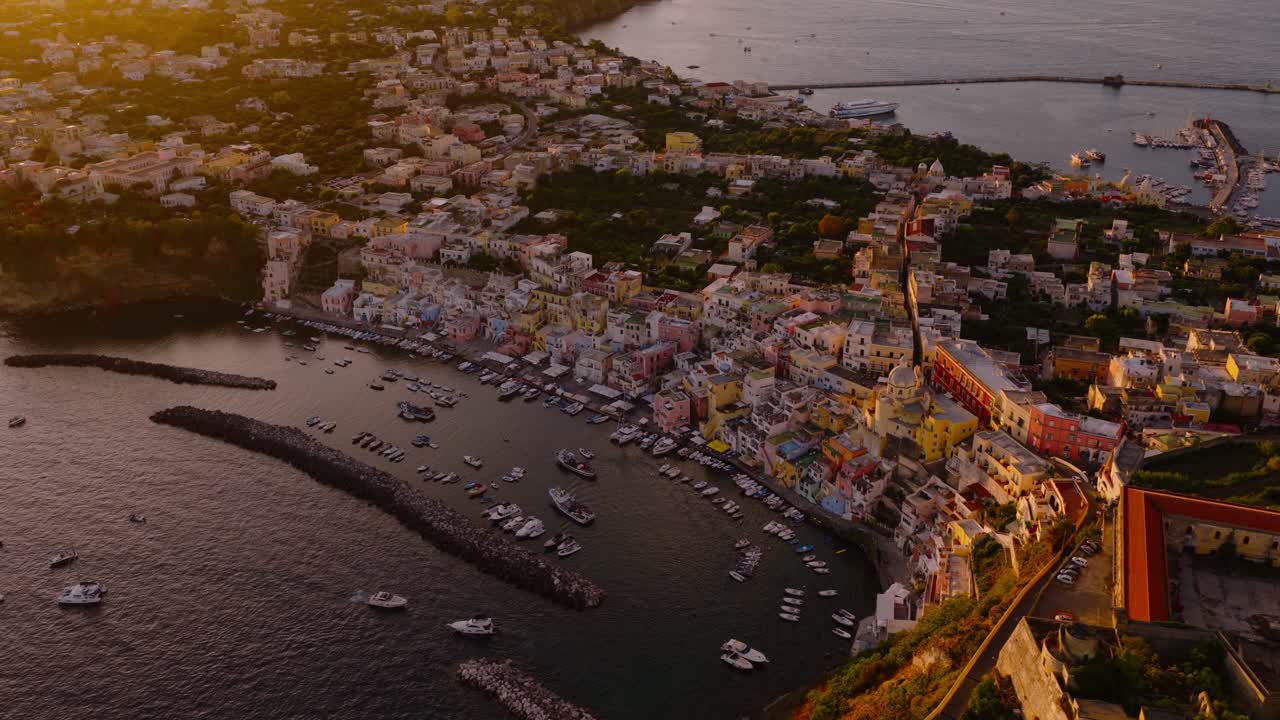 Porto de Corricella na ilha de Procida com casas coloridas ao pôr do sol nas Ilhas Flegreias, Nápoles, Itália - foto aérea