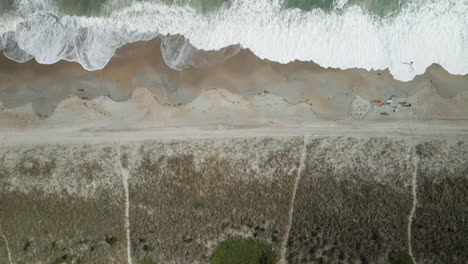 Vista-Aérea-De-Arriba-Hacia-Abajo-Que-Sigue-Las-Olas-Rompientes-Hasta-La-Costa-De-La-Playa-De-Wrightsville,-Carolina-Del-Norte