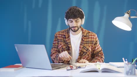 Young-man-who-does-not-like-to-study-gets-bored-and-picks-up-his-smartphone.