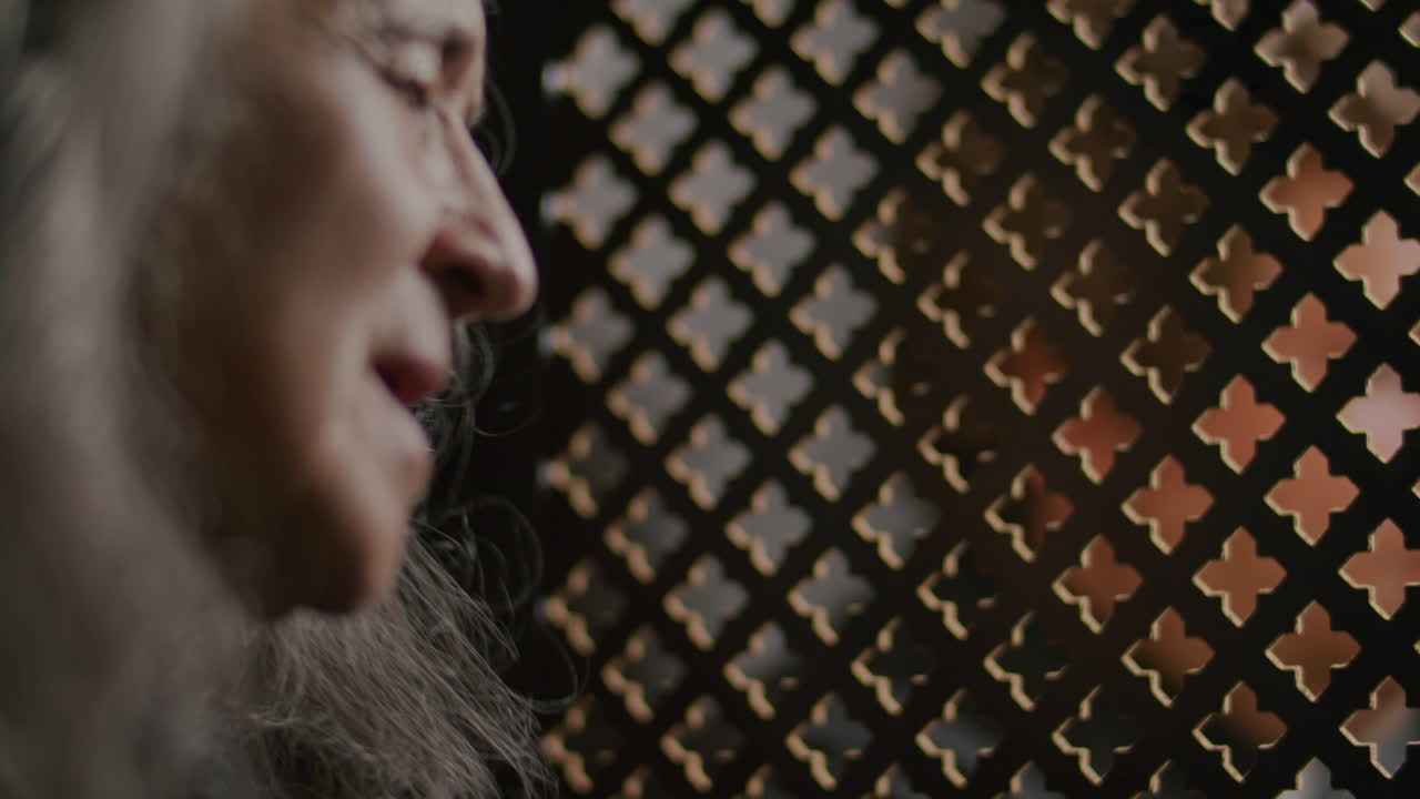 Senior Female Penitent Speaking with Priest in Confession Booth