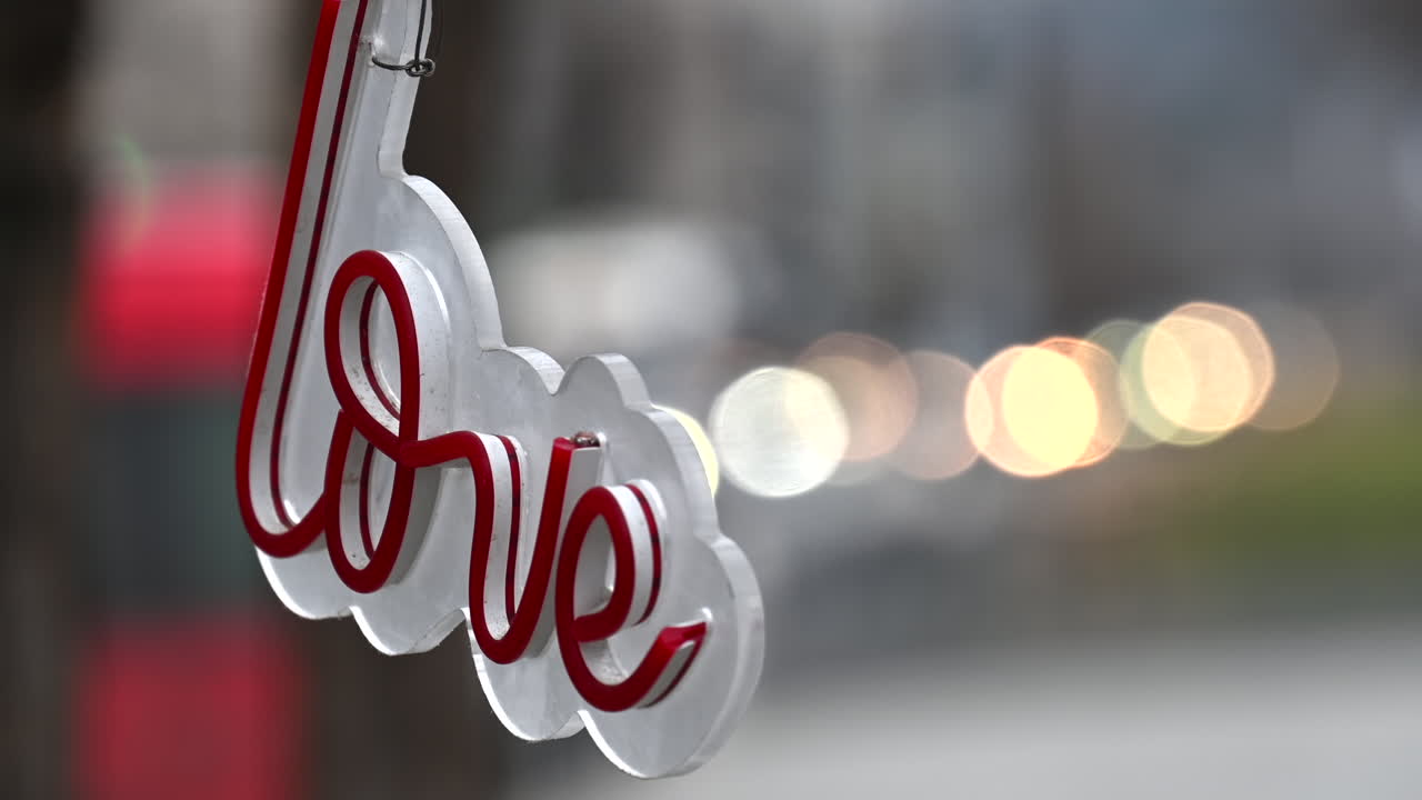 Neon sign with love writing in red hanging on the street