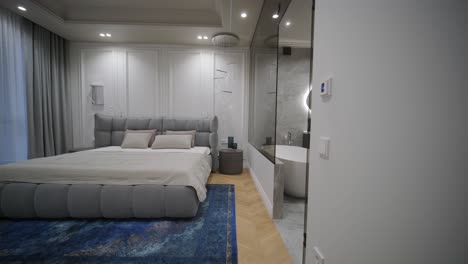 dormitorio de lujo con un cabecera de tuft y baño integrado con una bañera independiente y espejo iluminado