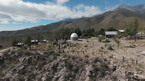 Aerial-above-mountain-village-with-astronomic-observatory-tower-and-scenic-landscape-in-Amaicha-del-Valle,-Argentina