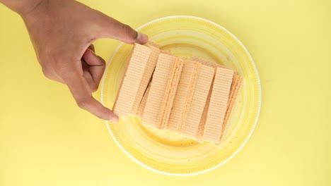 recogiendo a mano galletas de oblea de un plato