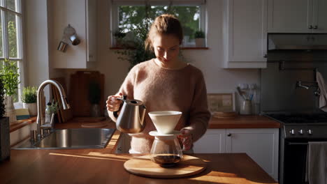 woman making pour-over coffee in a sunny kitchen