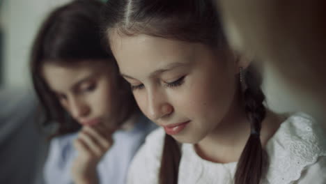 Two-schoolgirls-sitting-together-at-break-close-up.-Preteen-girls-looking-down.