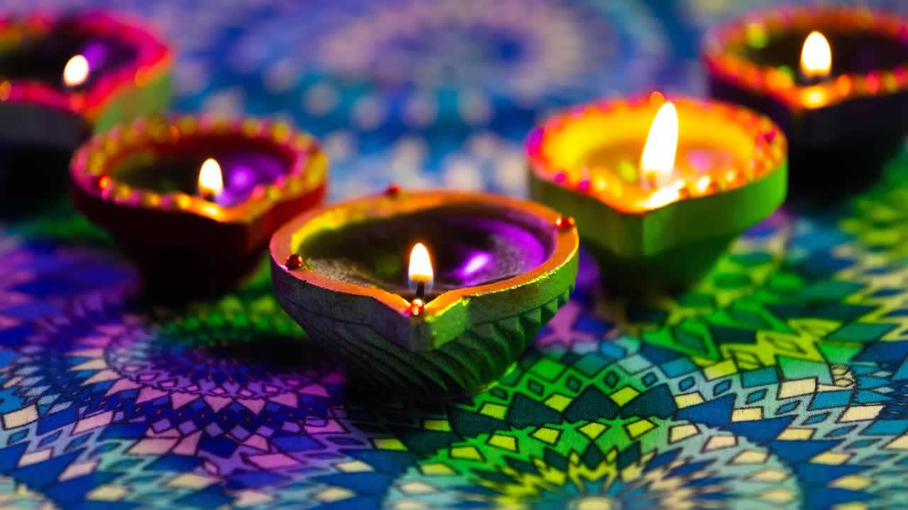 video de velas de diwali encendidas brillantes en una superficie con patrón de púrpura a verde