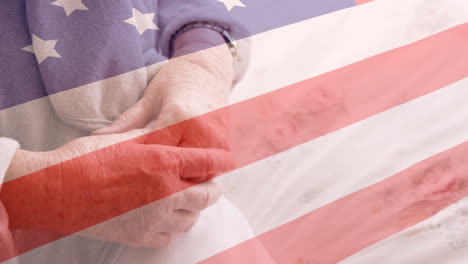 animation of flag of usa over senior caucasian female patient holding hands