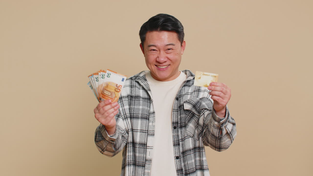 Happy asian man showing plastic credit bank card and money euro cash advertising taking loan