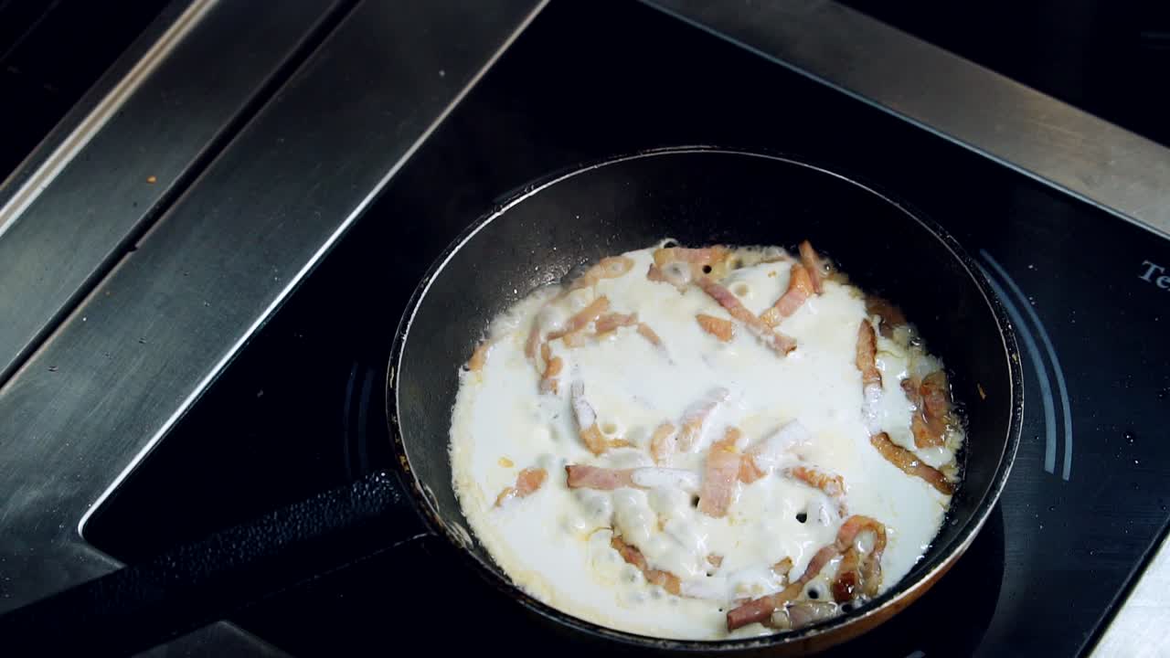 Frying tasty dish. Chef adding salt to bacon in sauce cooking in a frying pan. Process of making delicious food in the restaurant