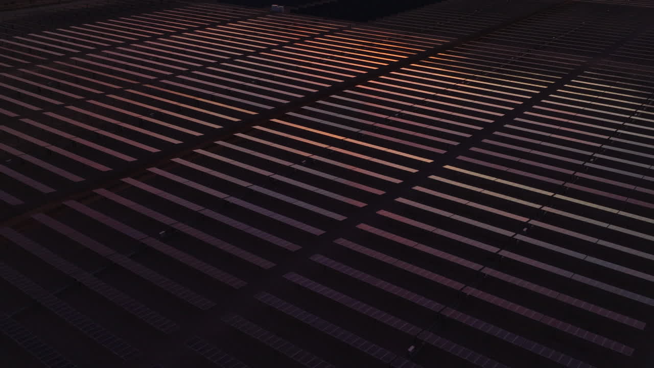 granja de paneles solares en un desierto que refleja la luz del amanecer o el anochecer, aérea
