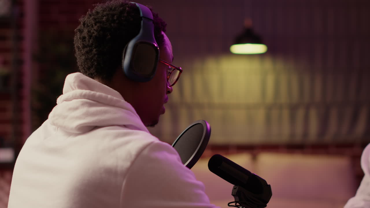 Afrikansk-amerikansk podcaster ses over skulderen, mens han selvsikkert taler under en liveudsendelse